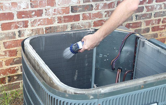 technician cleaning air conditioner condenser maintenance